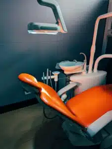 A dentist chair with an orange seat in a room A dentist chair with an orange seat in a room