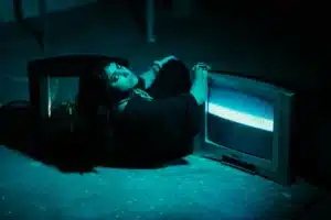 Woman lying between two old televisions - Sivi's Books Woman lying between two old televisions אישה שוכבת לצד שני טלוויזיונים ישנים, המסך פולט אור ורעש, תחושת עומס מדיה